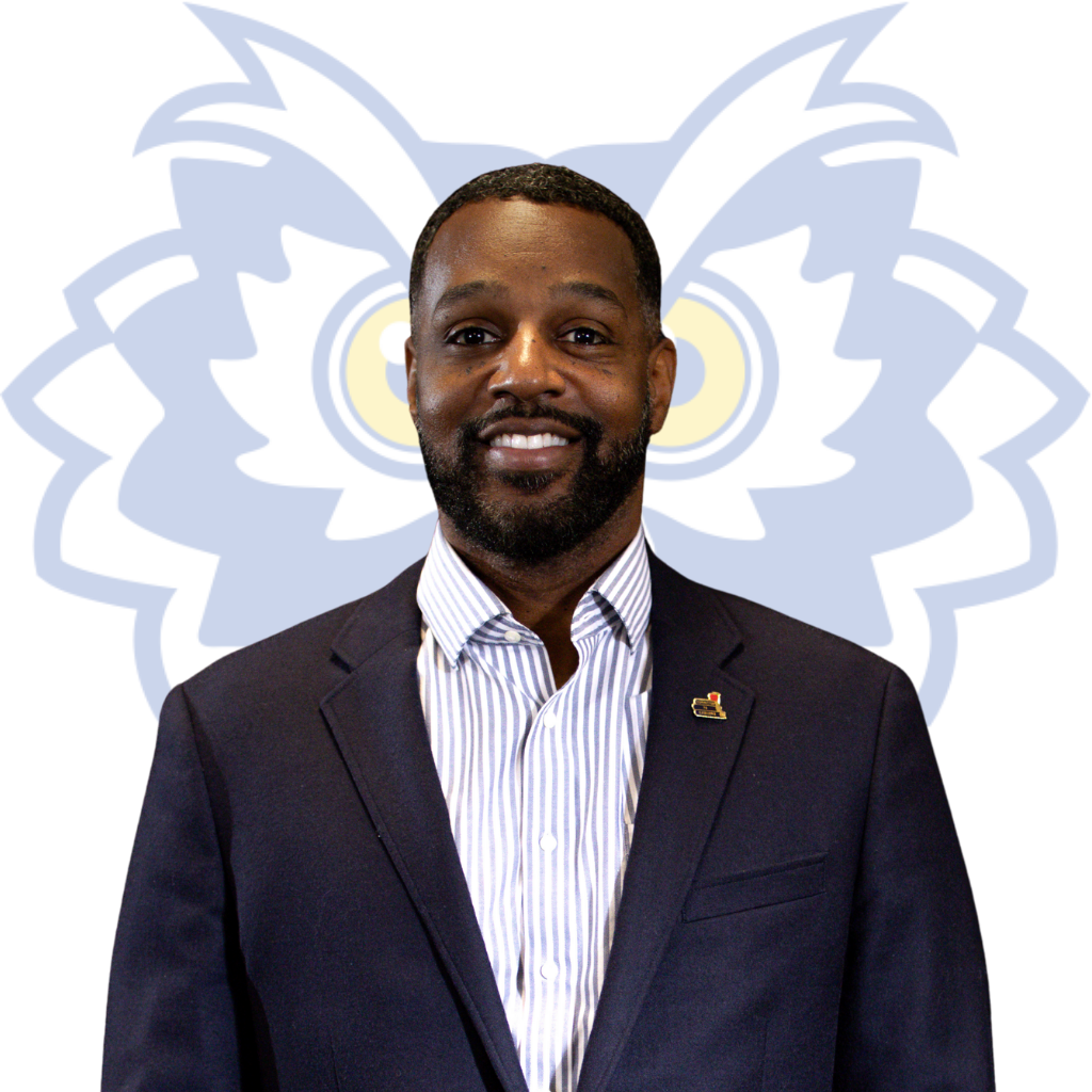 Portrait of Dr. Jeremy Coleman wearing a blue suit with a pinstripe undershirt. A light blue owl graphic is behind the person. 